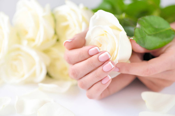 Kädet naisen kaunis ranskalainen manikyyri ja valkoisia ruusuja - Valokuva, kuva