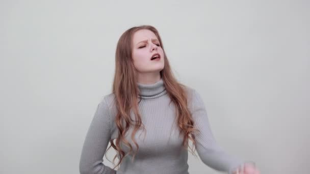 red-haired woman in a gray sweater shows a gesture of surprise and pretension - Footage, Video