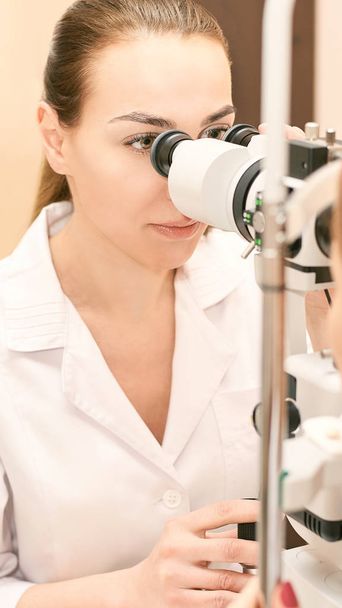 ophthalmologist doctor in exam optician laboratory with female patient. Eye care medical diagnostic. Eyelid treatment - 写真・画像