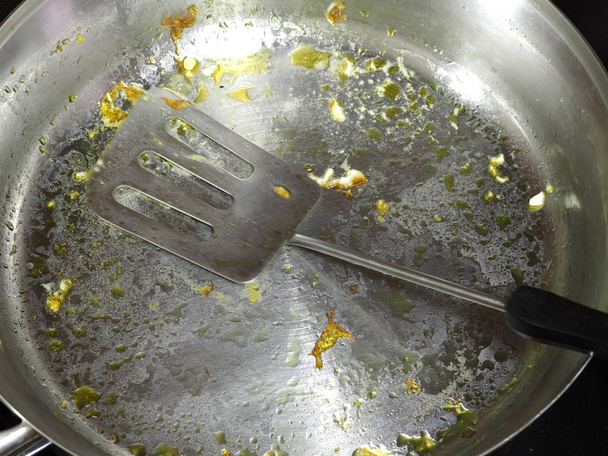 frigideira de aço inoxidável com espátula de panelas depois de fritar gemas de ovos
 - Foto, Imagem