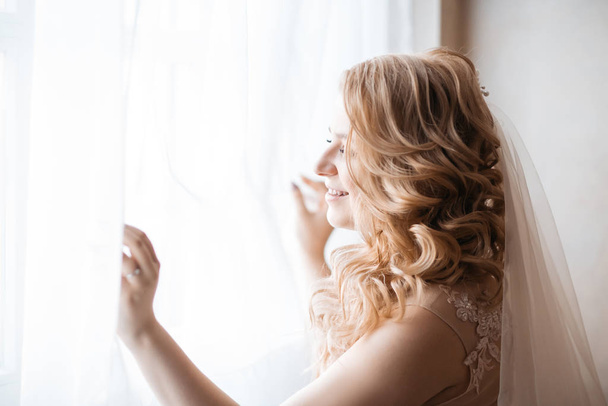 close up. young woman in wedding dress standing near the window. - Fotó, kép