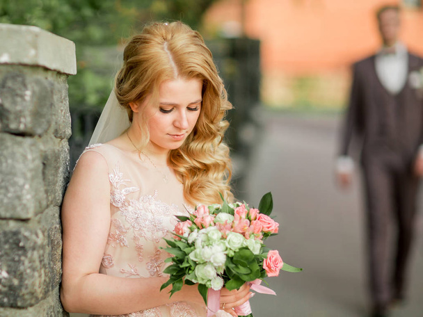 bride with a wedding bouquet standing on a city street. - Φωτογραφία, εικόνα