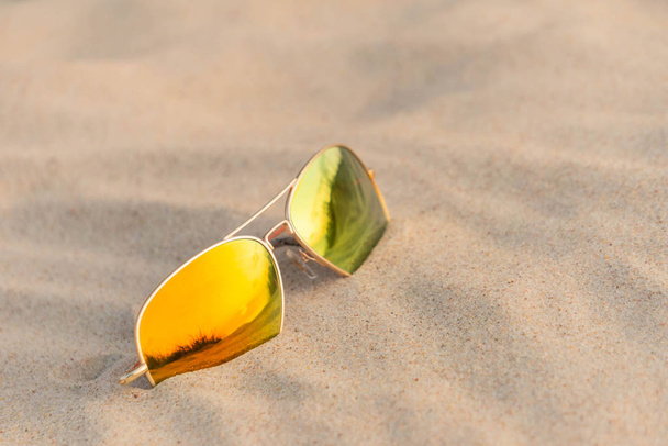 Sunglasses with dunes reflection in sand at beach in summertime vacation - Fotoğraf, Görsel