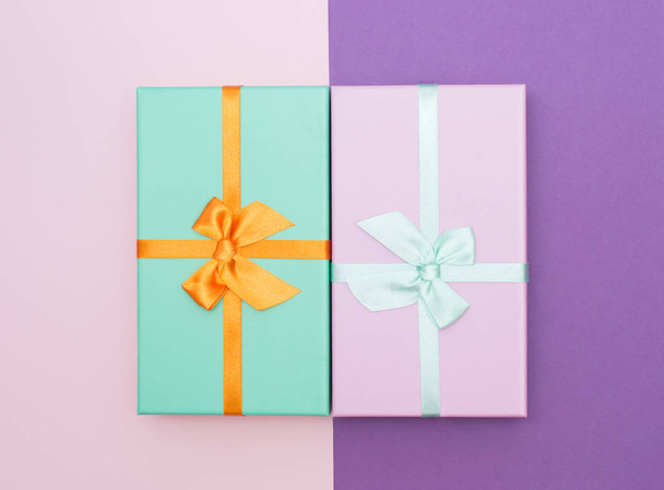 Flatlay with two colorful gift box with atlas ribbons on pink and purple background - Fotoğraf, Görsel