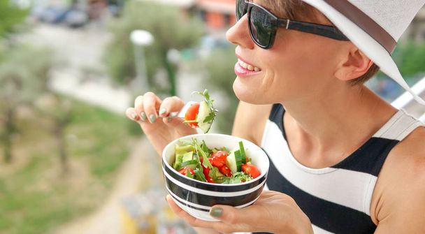 Gyönyörű nő eszik saláta áll a teraszon, erkély városi üdülőhely város - Fotó, kép