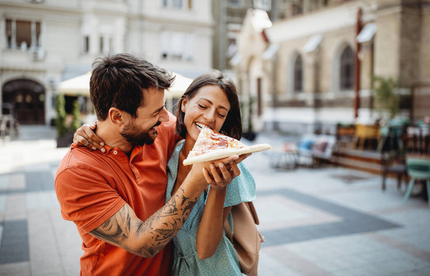 Feliz casal alegre comer pizza enquanto viaja de férias - Foto, Imagem