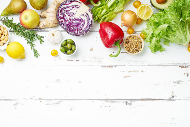 υγιεινά ωμά βιολογικά λαχανικά με βότανα και λαχανάκια με φρούτα σε λευκό ξύλινο τραπέζι. Φρέσκος κήπος χορτοφάγος έννοια τροφίμων  - Φωτογραφία, εικόνα