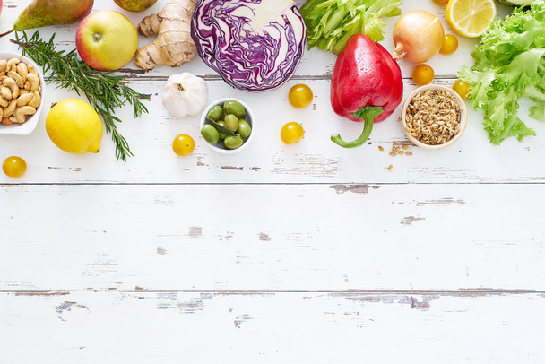 υγιεινά ωμά βιολογικά λαχανικά με βότανα και λαχανάκια με φρούτα σε λευκό ξύλινο τραπέζι. Φρέσκος κήπος χορτοφάγος έννοια τροφίμων  - Φωτογραφία, εικόνα