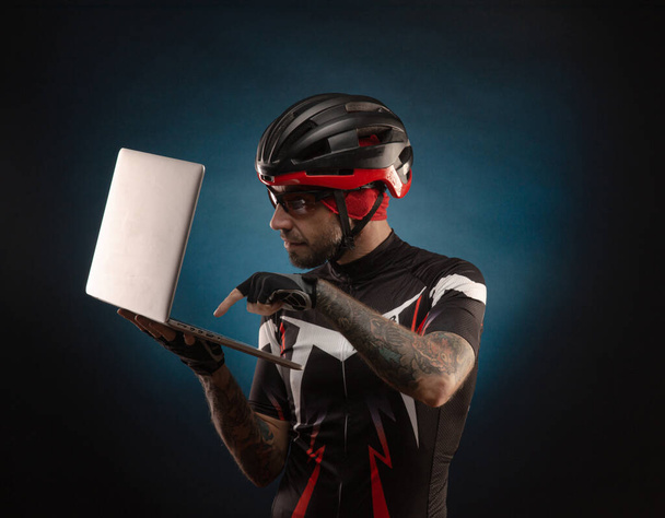 férfi-kerékpáros egy kerékpáros sisak egy laptop - Fotó, kép