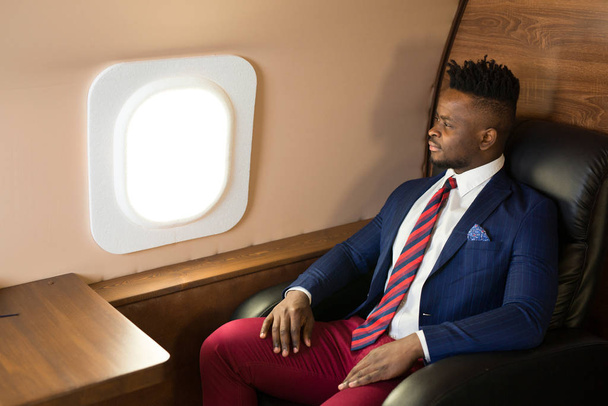 handsome african young man in suit in private jet cabin - Photo, Image