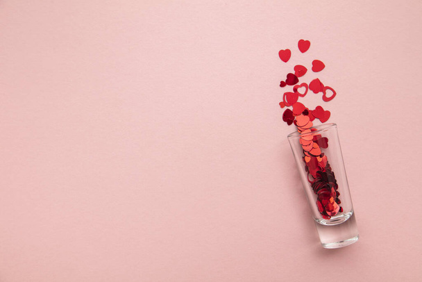 Valentines day shots. Shot glass with heart confetti on pastel pink background - Zdjęcie, obraz