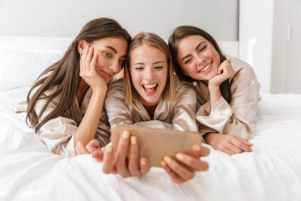 Three cheerful girls friends wearing dressing gowns - Фото, зображення