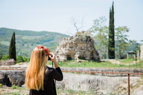 Fiatal női utazó, aki ősi romokat fényképez Toszkánában, Olaszországban. - Fotó, kép