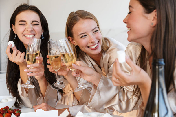 Cheerful young girls women drinking champagne eat fruits. - Photo, Image
