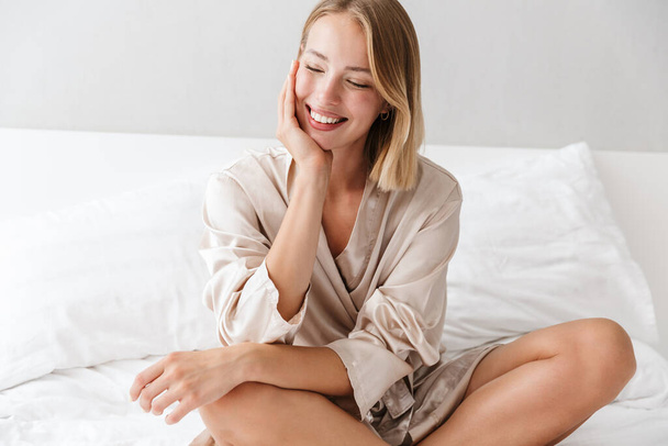 Cheery young woman indoors on bed at home. - Foto, Bild