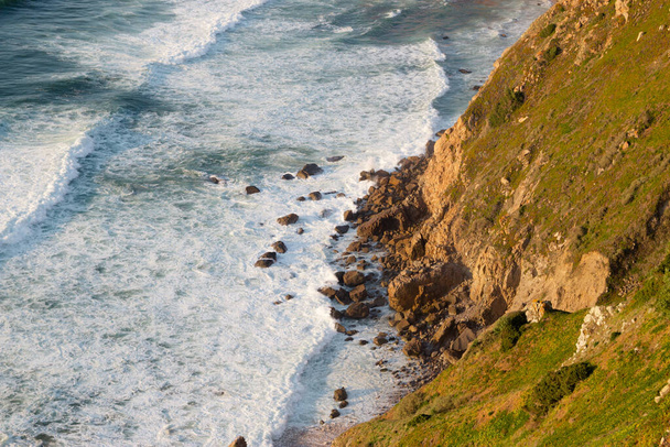 Waves, cliffs and rocks in rays of setting sun on Cabo da Roca, Portugal. - Zdjęcie, obraz
