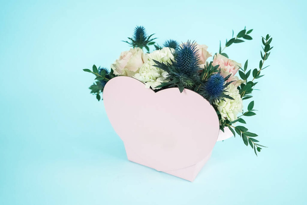 A gift for lovers on Valentines Day. Pink heart on a turquoise background. Cute pink heart-shaped basket for a bouquet - 写真・画像