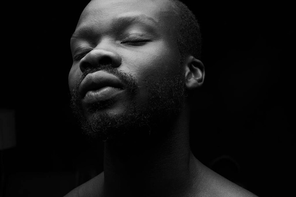 black and white portrait of a handsome black man with closed eyes on dark background - Valokuva, kuva