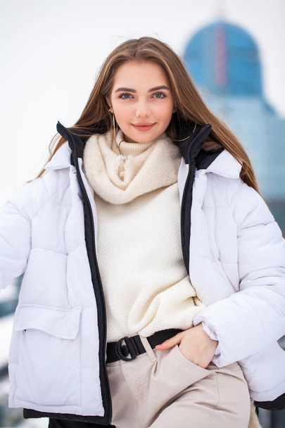 Fshion girl in a white down jacket and beige pants posing outdoo - Foto, immagini