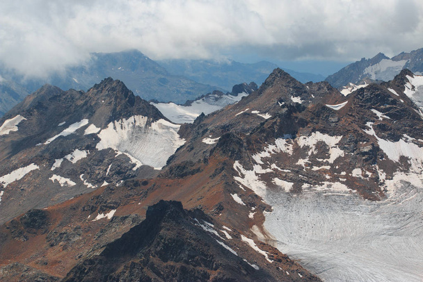 Caucasus mountains near Elbrus volcano with glaciers, clouds and peaks. - Foto, Bild