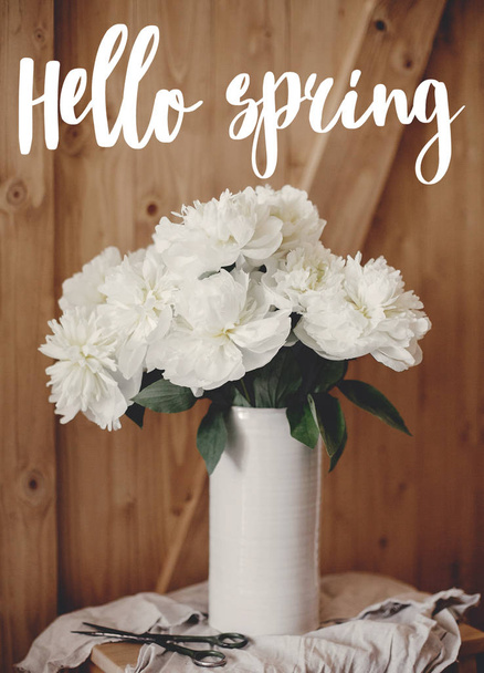 Hello spring text. Stylish peony bouquet in vase on linen fabric - Fotó, kép
