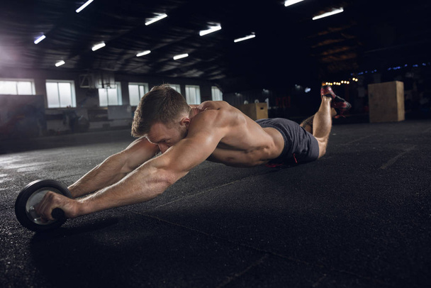 Young healthy male athlete doing exercises in the gym - Photo, image