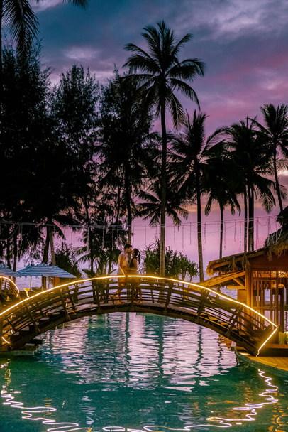 ビーチで夕日を眺めるカップルとタイの高級リゾートのプール｜カオラック - 写真・画像