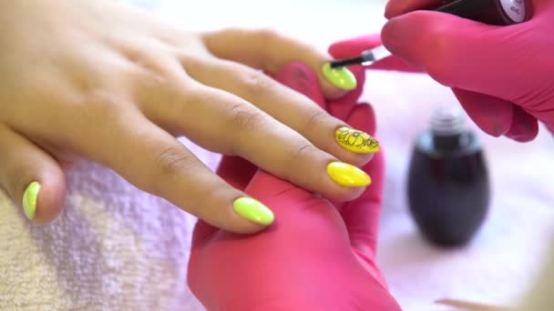 Nahaufnahme einer Kosmetikerin beim Auftragen von Nagellack auf weibliche Nägel in einem Nagelstudio Nahaufnahme einer Frauenhand mit gelbem Nagellack nach der Maniküre  - Filmmaterial, Video