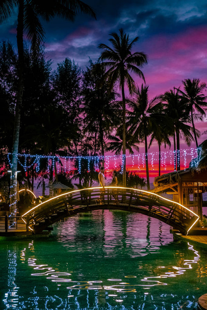 ζευγάρι βλέποντας ηλιοβασίλεμα από την παραλία και την πισίνα ενός πολυτελούς θέρετρου στην Ταϊλάνδη Khao Lak - Φωτογραφία, εικόνα