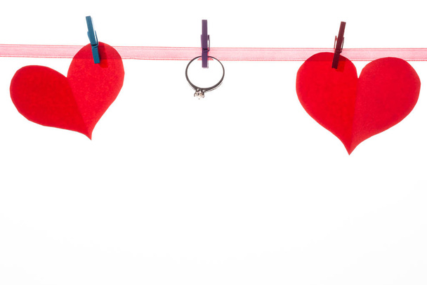 Rode papieren hartjes op wasknijpers op een witte achtergrond. Valentijnsdag en huwelijksaanzoek concept. - Foto, afbeelding