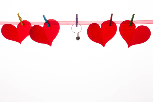 Rode papieren hartjes op wasknijpers op een witte achtergrond. Valentijnsdag en huwelijksaanzoek concept. - Foto, afbeelding