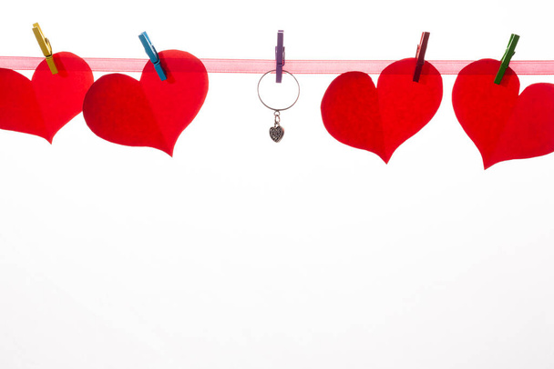 Κόκκινες χάρτινες καρδιές σε μανταλάκια σε λευκό φόντο. Έννοια του Αγίου Βαλεντίνου και πρόταση γάμου. - Φωτογραφία, εικόνα