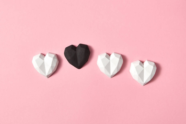 Valentine's creative composition from gypsum white hearts and one is black on a light pink background, copy space. Greeting card. - Zdjęcie, obraz