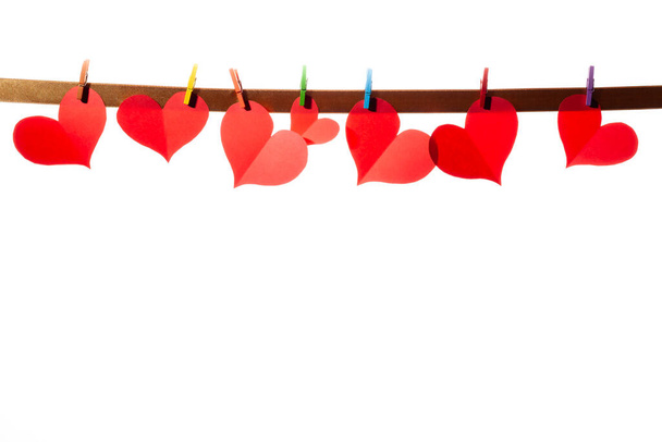Κόκκινες χάρτινες καρδιές σε μανταλάκια σε λευκό φόντο. Ημέρα του Αγίου Βαλεντίνου έννοια. - Φωτογραφία, εικόνα