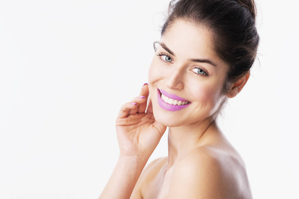 Headshot of gorgeous young woman with perfect skin wearing purple lipstick while posing at isolated white background with copy space.  - Photo, Image
