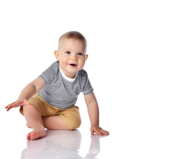 Gelukkig glimlachende baby jongen peuter in t-shirt en broek is beginnen kruipen naar op alle vier op wit met kopieerruimte  - Foto, afbeelding
