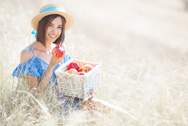 Attractive young woman on summer background. Smiling female portrait. Beautiful lady outdoors holding apples. - Foto, afbeelding