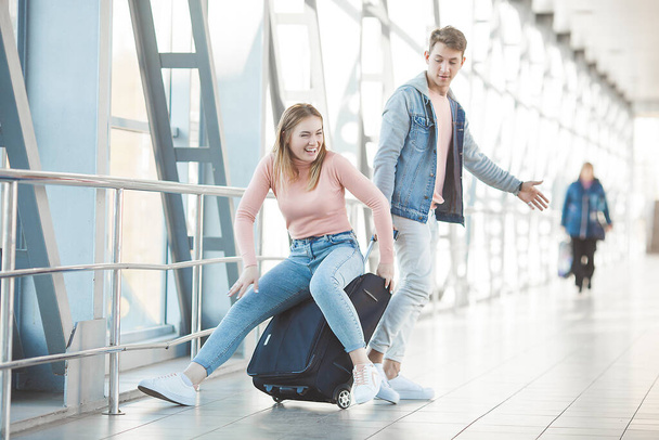 Šťastný mladý pár na letišti terminálu baví při čekání na svůj let. Dva lidé muž a žena se chystají zakopnout. - Fotografie, Obrázek