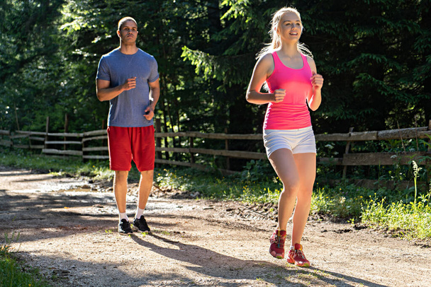 Запуск фитнес-пара бегунов, занимающихся спортом на улице. Активный живой мужчина и женщина бег трусцой тренировки кардио летом на природе
. - Фото, изображение