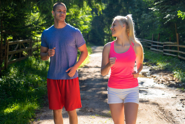 Bieganie fitness para biegaczy uprawiających sport na drodze na zewnątrz. Aktywne życie mężczyzna i kobieta jogging szkolenia cardio w lecie na świeżym powietrzu natura. - Zdjęcie, obraz
