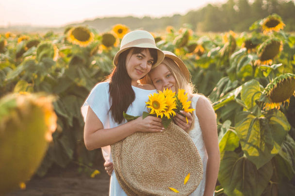 Happy mother and her teenager daughter in the sunflower field. Outdoors lifestyle happiness - Photo, Image