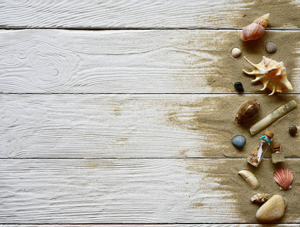 Conchas marinas, guijarros y arena sobre un fondo de madera blanca. Vista superior. Fondo de verano
. - Foto, imagen