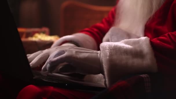 Nahaufnahme aus der Hand: Ein älterer Weihnachtsmann mit weißem Bart sitzt auf einem Stuhl und betreibt Internet-Banking. Ihre Konten und E-Mails einsehen. - Filmmaterial, Video