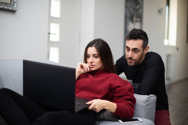 Portrait of an happy couple using a laptop computer in their house - Fotó, kép