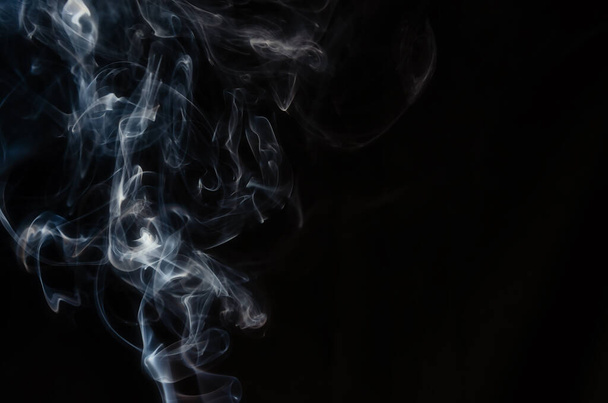 Abstract figure made of smoke on the left side of the frame on a dark background with place for text. - Fotó, kép