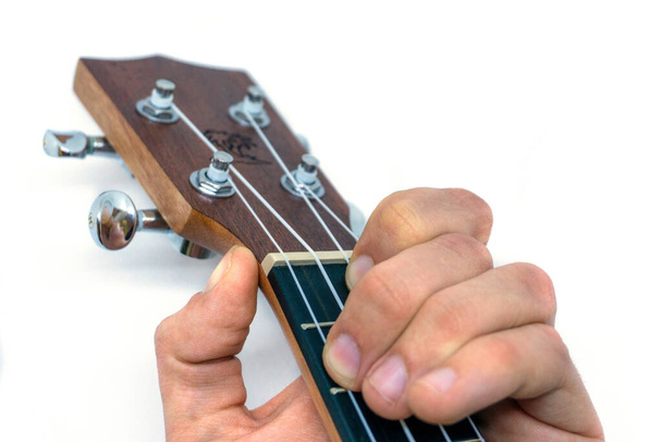 Kézfogás egy fa ukulele fehér háttér. - Fotó, kép