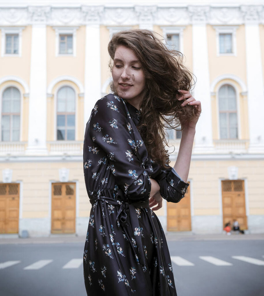 1 white young woman with brown wavy hair in a brown dress on the - Valokuva, kuva