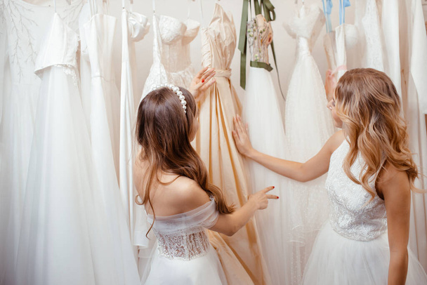 duas jovens mulheres escolhendo vestido para o casamento
 - Foto, Imagem