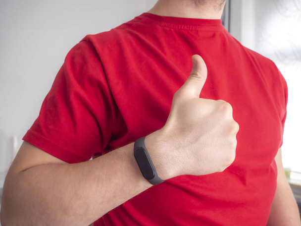 A man wears a fitness bracelet on his hand. Using a pedometer. Electronics for measuring heart rate. - Photo, Image