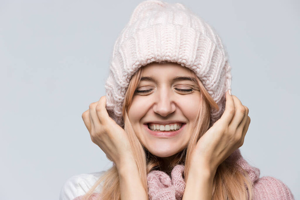 Close up studio portrait of attractive joyfully smiling girl in pink sweater and white hat, dressed casually/ good-looking beautiful woman, positive emotions after receiving pleasant compliment. - Zdjęcie, obraz